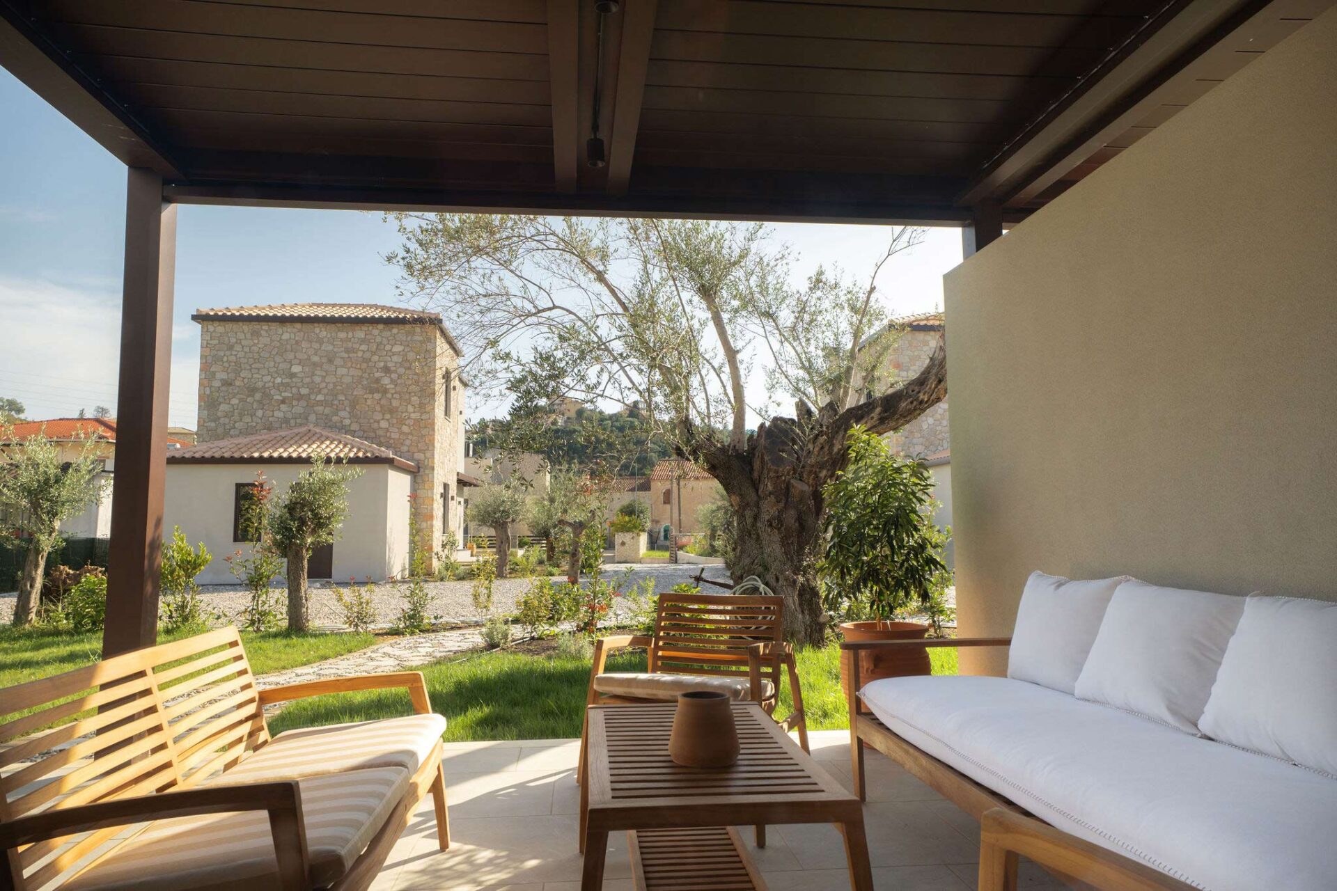 Modern patio furniture on a stone-paved terrace surrounded by Mediterranean greenery