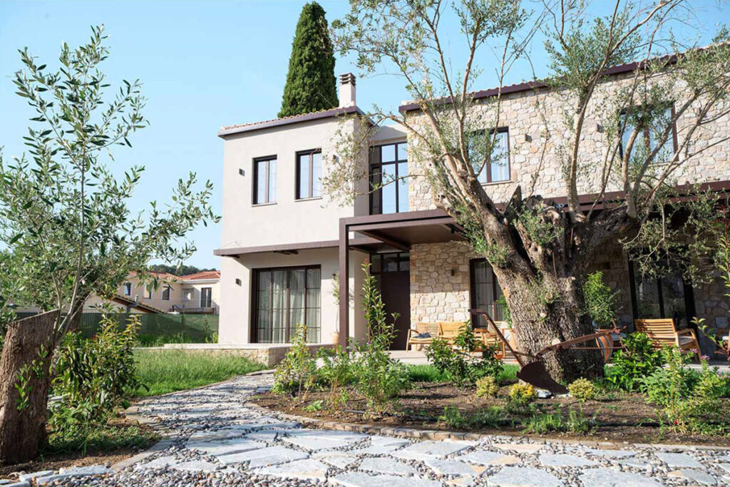 Lush Mediterranean garden with blooming flowers and stone pathways surrounding Kepos Villas.