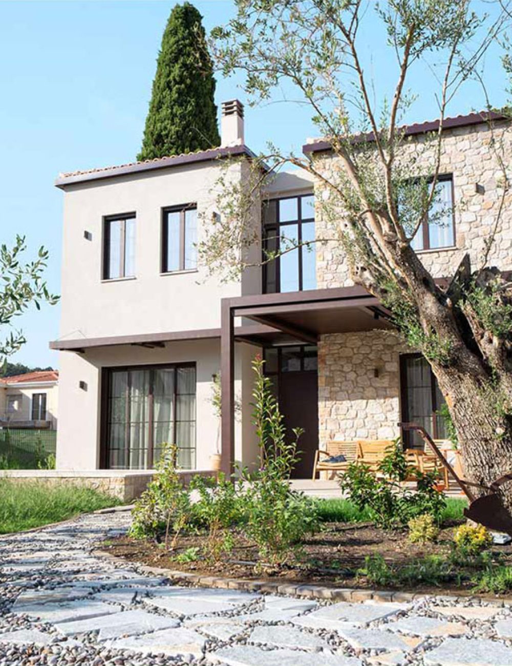 Lush Mediterranean garden with blooming flowers and stone pathways surrounding Kepos Villas.