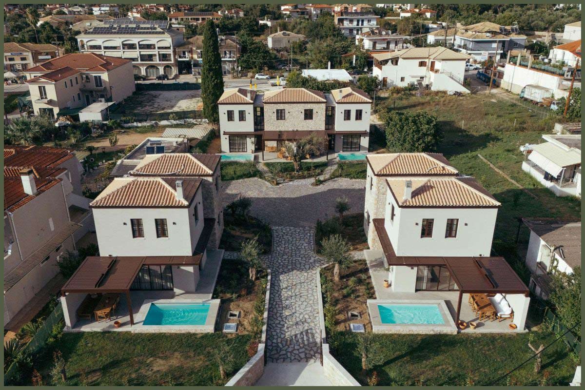 Lush Mediterranean garden with blooming flowers and stone pathways surrounding Kepos Villas.